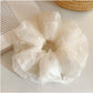 Soft beige tulle scrunchie with gathered fabric detail on a white background