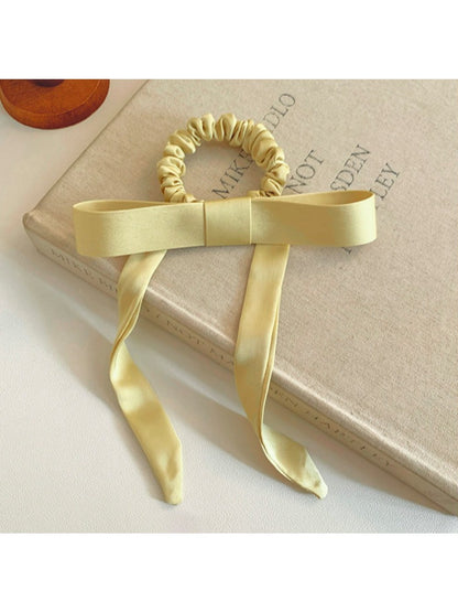Side view of Gifty satin yellow ribbon bow scrunchie highlighting fabric texture