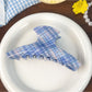 Blue plaid shark hair claw clip placed on wooden surface