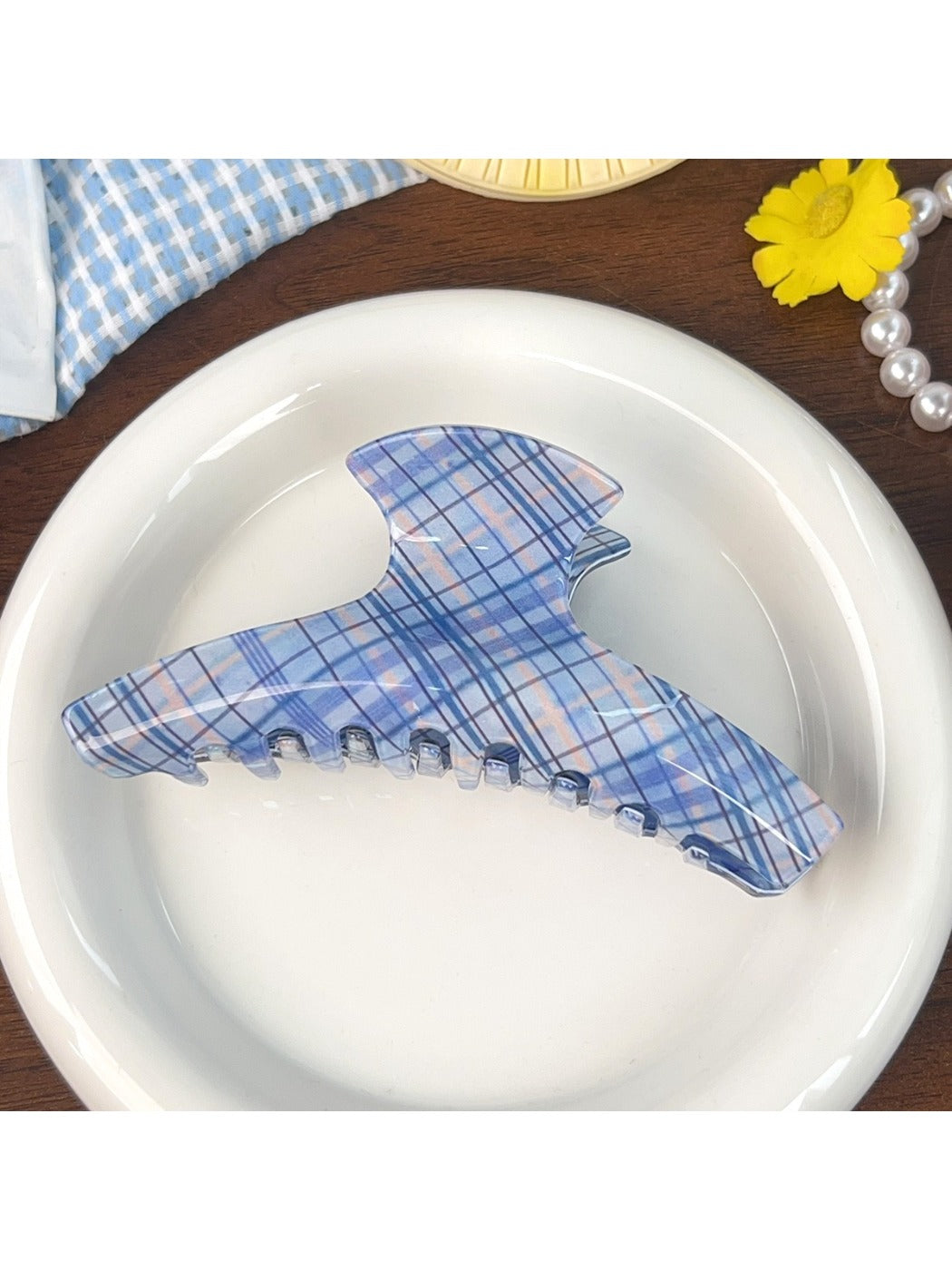 Blue plaid shark hair claw clip placed on wooden surface