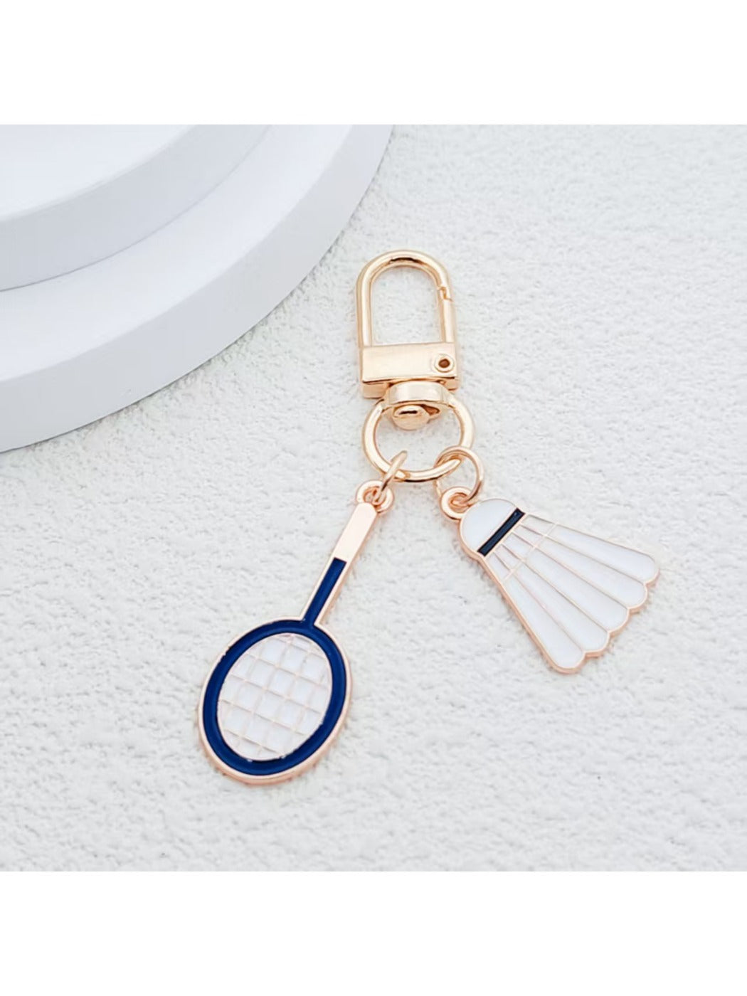 Side angle of alloy badminton shuttlecock keychain showing smooth metallic texture