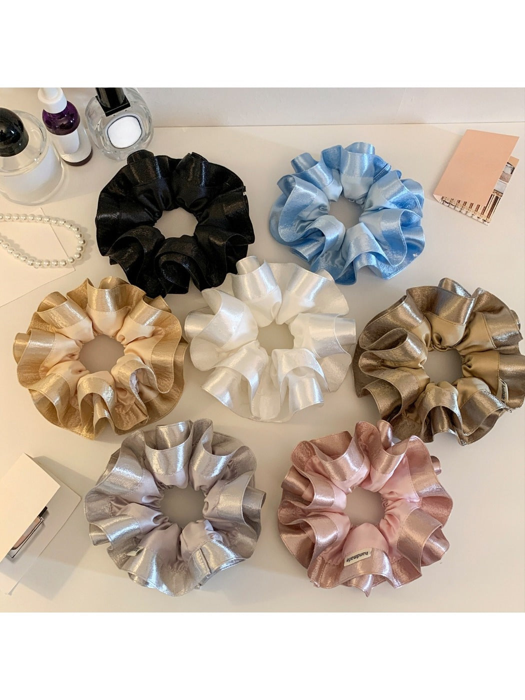 Close-up of Gifty elegant satin ruffle scrunchie in soft pink on white background