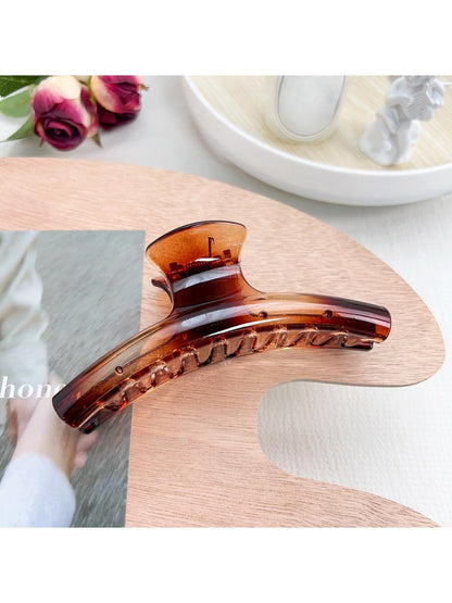 Pastel curved claw clip placed on wooden surface with natural lighting