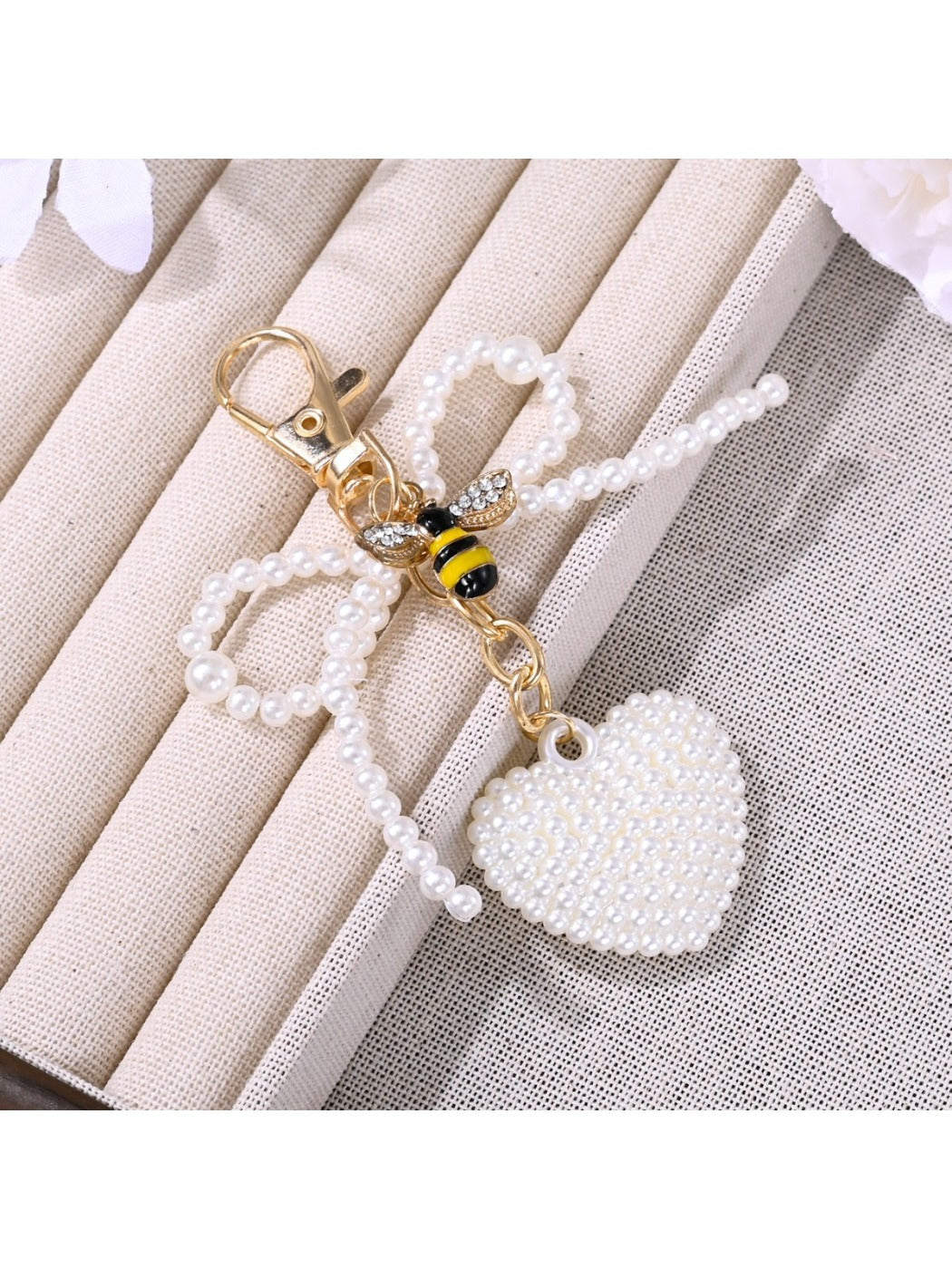 Pink bow heart shaped keychain hanging from a handbag strap