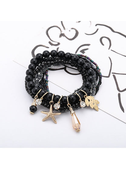Multiple Lovra stackable bracelets layered on wrist featuring ocean-themed pendants