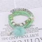 Lovra beaded bracelet with pompom pendant laid flat on white background