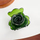 Beau flower-shaped claw clip in light gray shown from an angled perspective