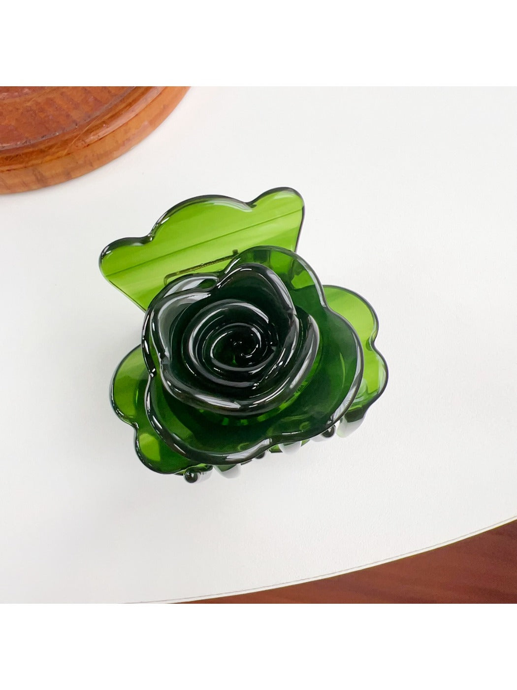 Beau flower-shaped claw clip in light gray shown from an angled perspective