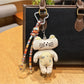 Keypus bunny charm keychain with pink ears and smiling face on a plain surface