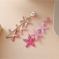 Earedge star pendant earrings displayed on a jewelry stand