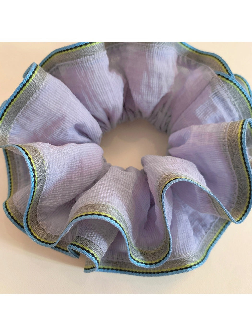 Purple scrunchie styled on a wrist as a bracelet