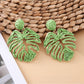 Model wearing raffia woven hollow leaf shaped earrings with a neutral outfit
