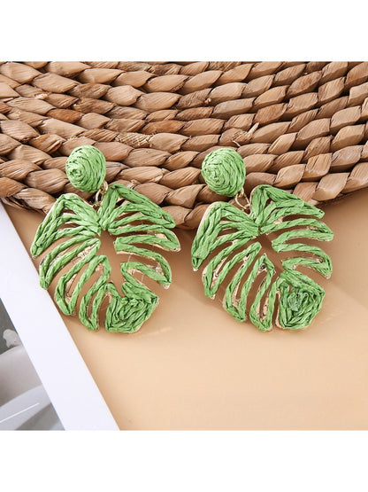 Model wearing raffia woven hollow leaf shaped earrings with a neutral outfit