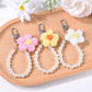 Close-up of a yarn flower keychain with colorful beads on a white background