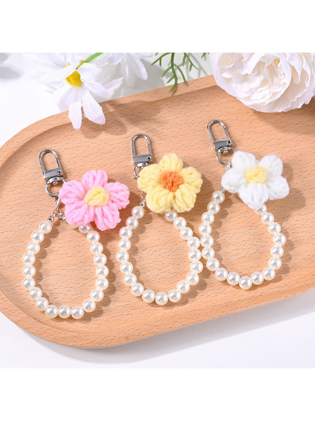 Close-up of a yarn flower keychain with colorful beads on a white background