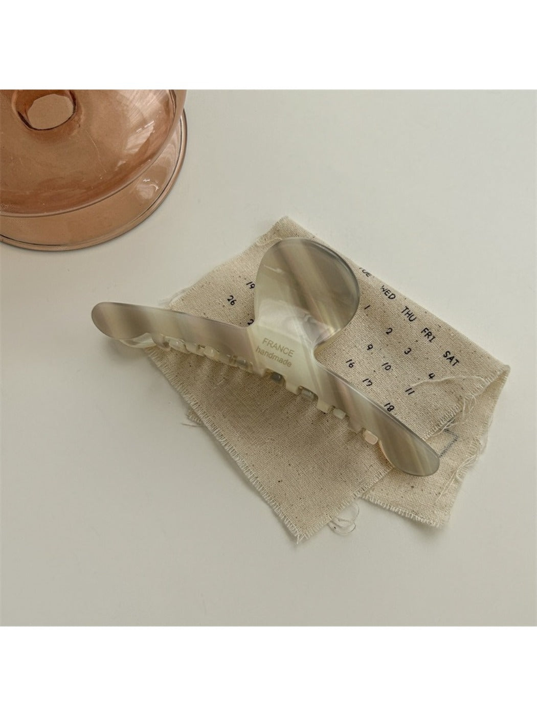 Beau chic acetate claw clip resting on a wooden surface with natural light