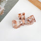 Beau claw clip in dark brown color placed on a marble countertop