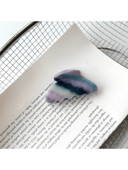 Beau purple hair claw clip held in hand showing size and shape