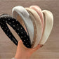 Sweet wide edge headband with white polka dots on a pastel pink background
