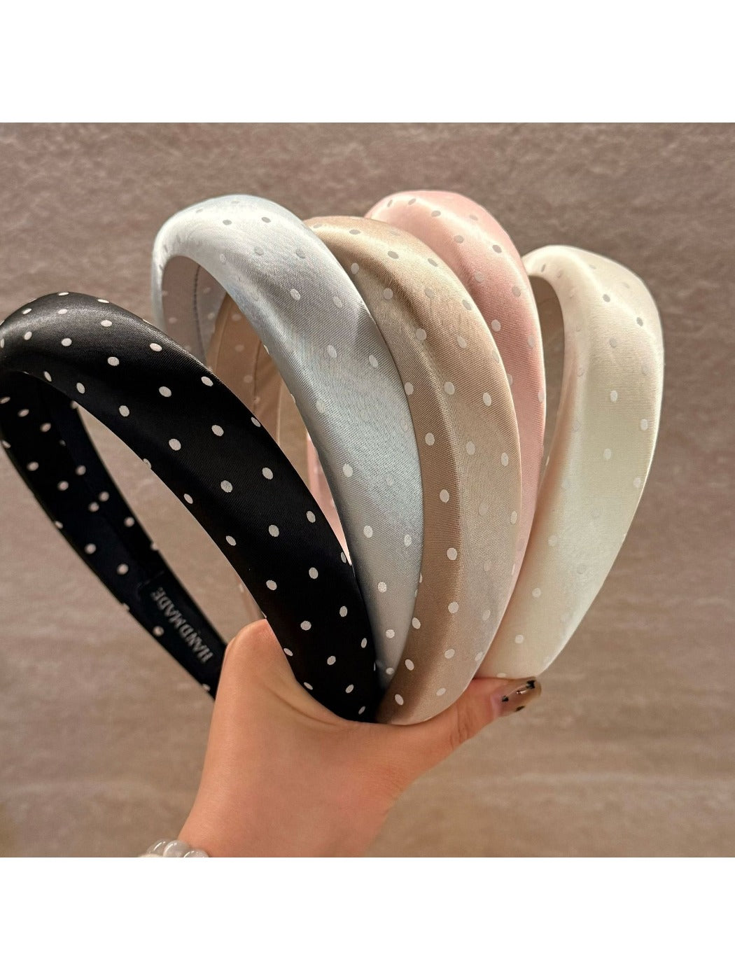 Sweet wide edge headband with white polka dots on a pastel pink background