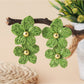 Model showcasing earedge raffia flower drop earrings with short hair