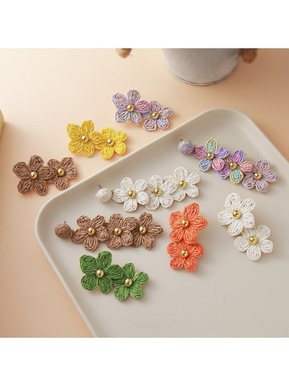 Close-up of flower shaped raffia drop earrings with natural beige fibers