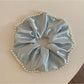 Close-up of Gifty chic satin scrunchie with pearl beads on a white background