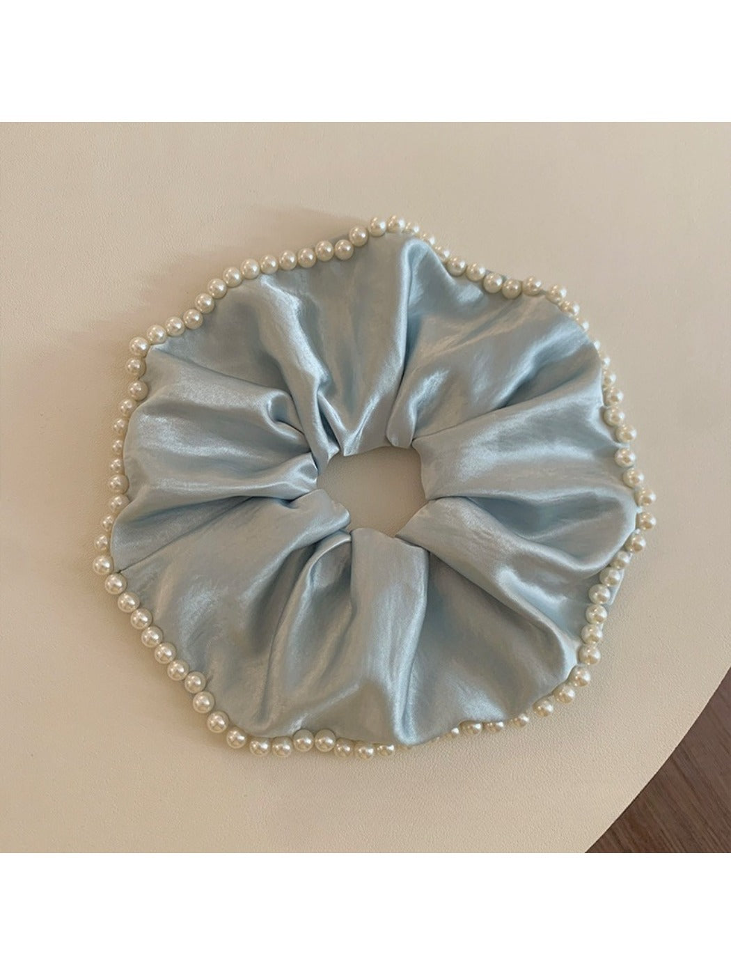Close-up of Gifty chic satin scrunchie with pearl beads on a white background
