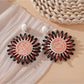 Pink and black raffia woven earrings held in hand showing size and detail