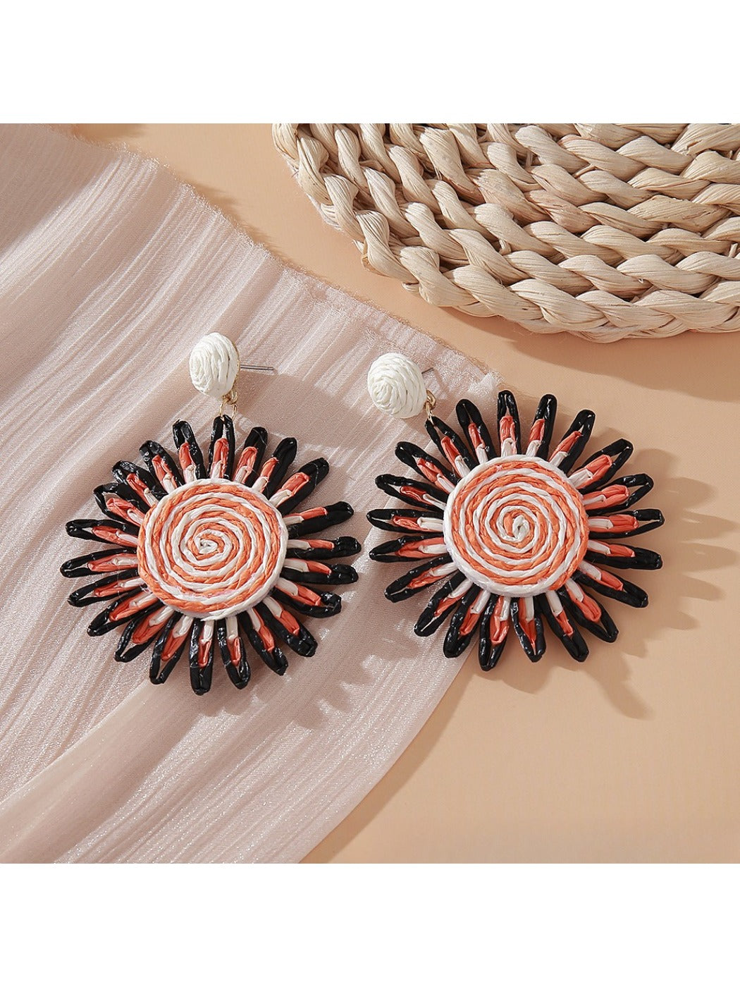 Pink and black raffia woven earrings held in hand showing size and detail
