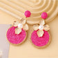 Pair of Earedge chic circular floral drop earrings hanging from a jewelry stand