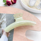 Pastel curved claw clip held against light showing translucent pastel colors