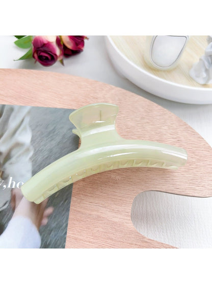 Pastel curved claw clip held against light showing translucent pastel colors