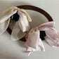 Beau bow ribbon streamer claw clip worn in long brown hair styled in loose waves