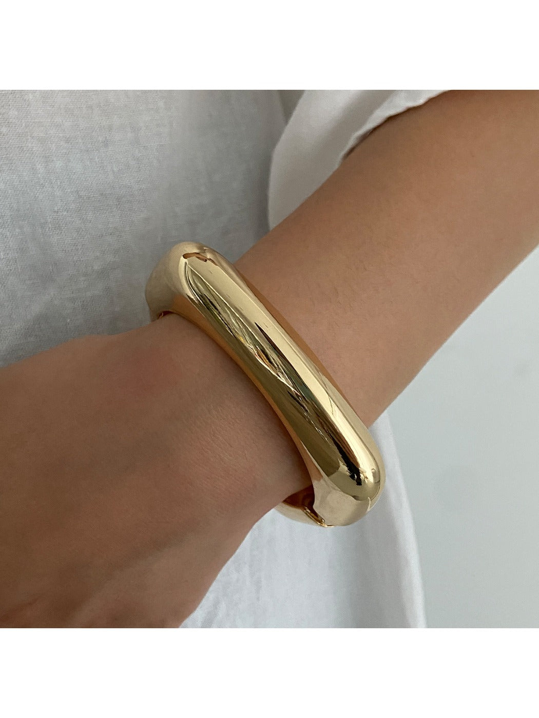 Lovra wide round bangle bracelet displayed on a hand model to show size and fit