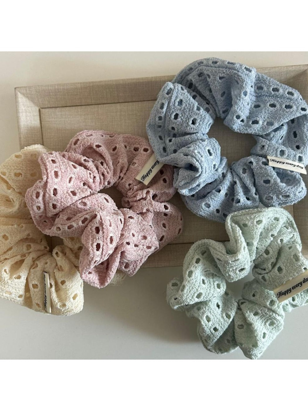 Beige scrunchie with soft texture and subtle dot cutouts displayed on white background