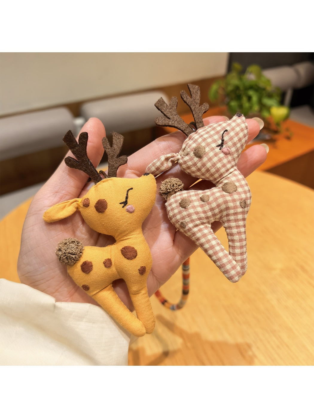 Deer charm keychain attached to a leather bag zipper pull
