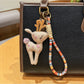 Keypus deer charm keychain photographed with a blurred green outdoor background