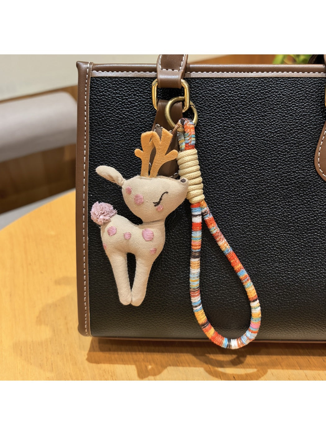 Keypus deer charm keychain photographed with a blurred green outdoor background