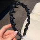 Elegant wavy headband adorned with small white beads on a plain background