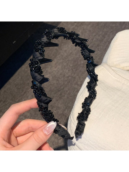 Elegant wavy headband adorned with small white beads on a plain background