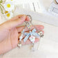 Floral bow charm keychain attached to a set of keys on a wooden surface