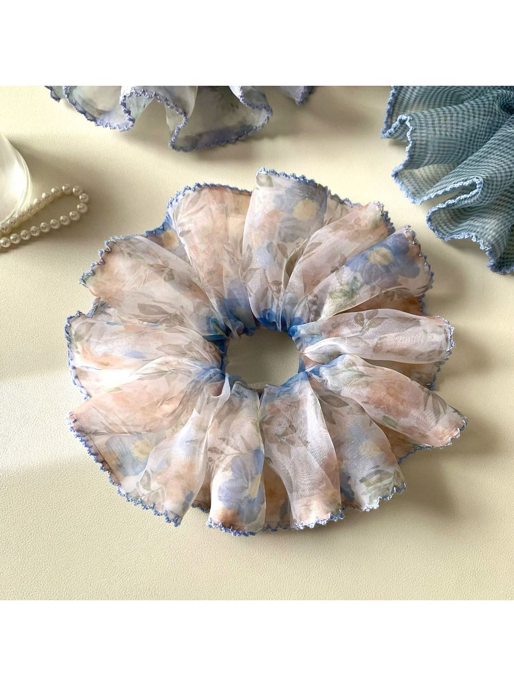 Blue scrunchie featuring a delicate vintage pattern held in hand