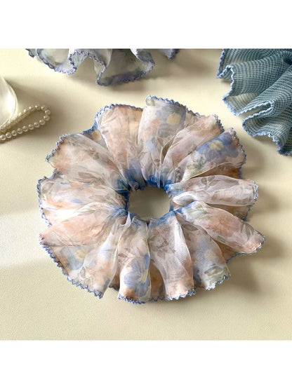 Blue scrunchie featuring a delicate vintage pattern held in hand