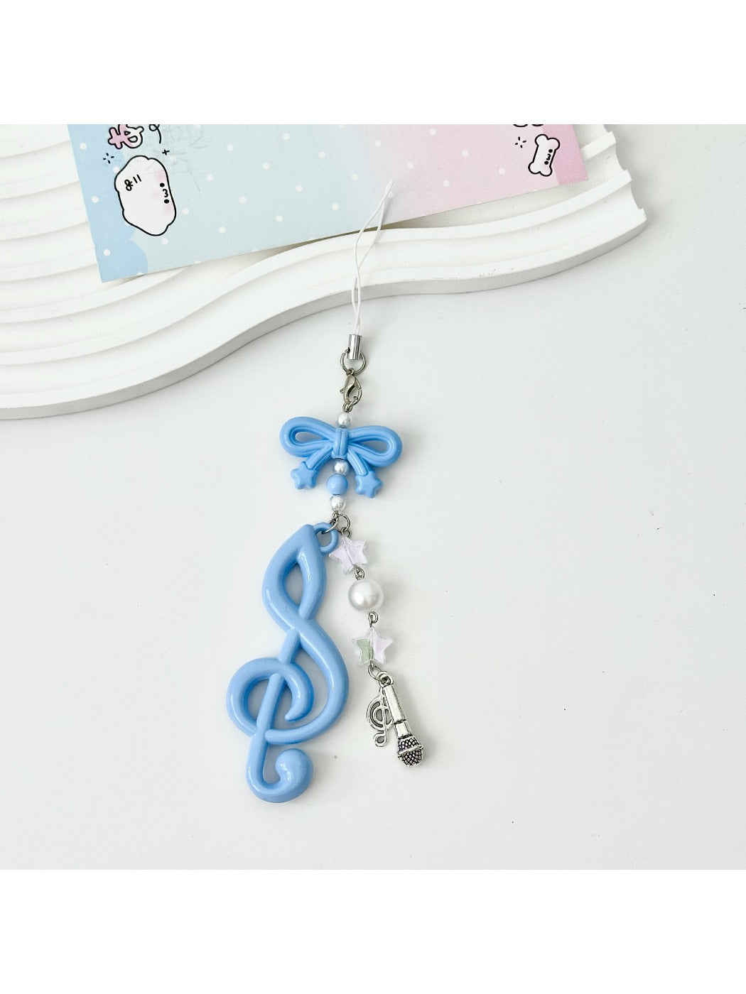 Keypus music note keychain lying flat with a soft shadow on a white surface