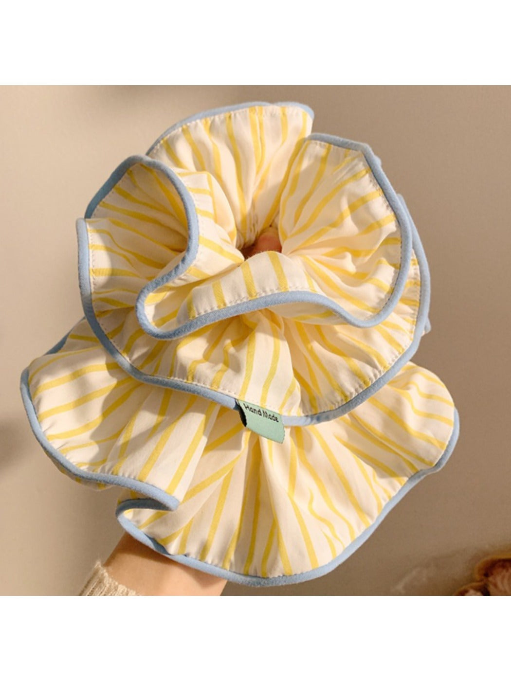 Yellow striped scrunchie wrapped around a ponytail on a model