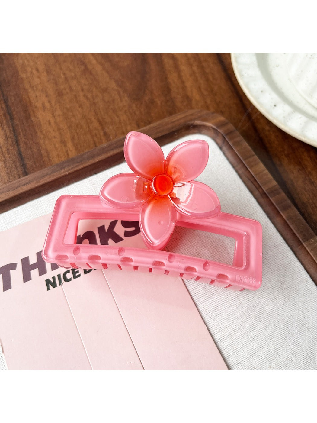 Beau square ombre flower shaped claw clip placed on wooden surface showing top floral design