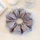 Close-up of a chic satin ruched scrunchie in soft pink fabric