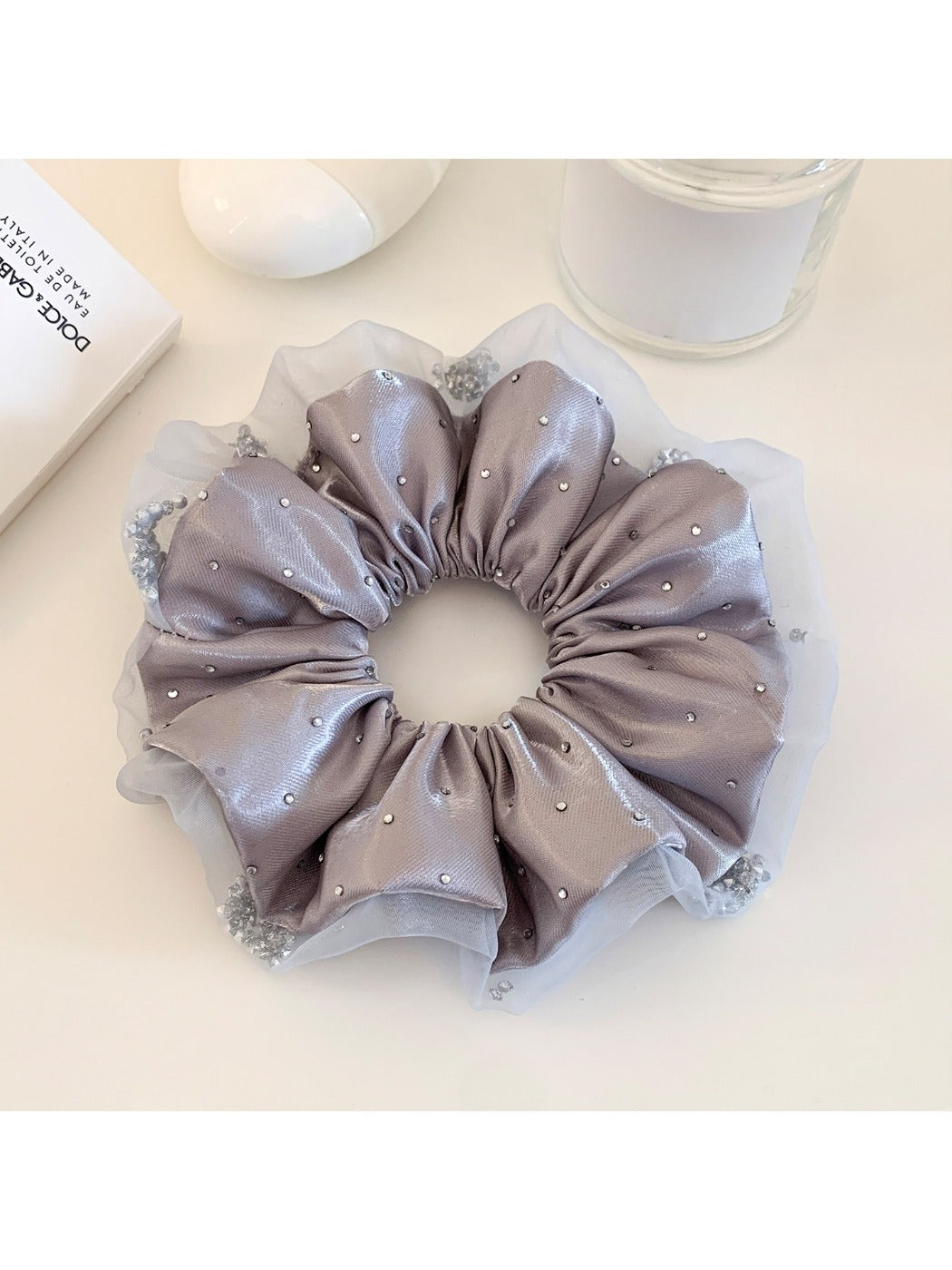 Close-up of a chic satin ruched scrunchie in soft pink fabric
