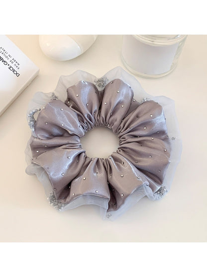 Close-up of a chic satin ruched scrunchie in soft pink fabric